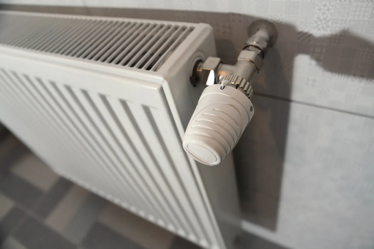 Weißer Heizkörper mit Thermostatventil, eingestellt auf eine niedrigere Stufe.