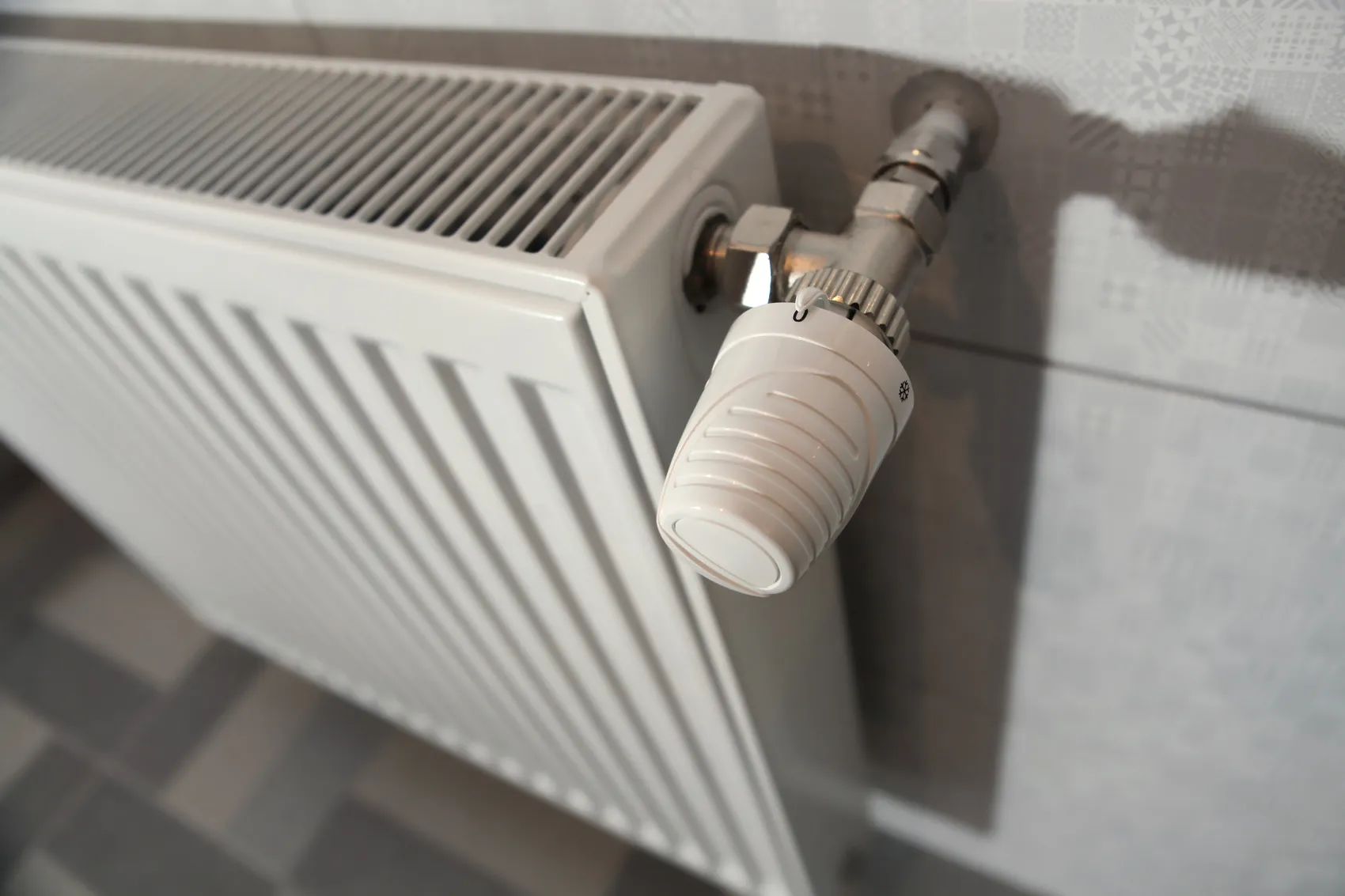 Weißer Heizkörper mit Thermostatventil, eingestellt auf eine niedrigere Stufe.