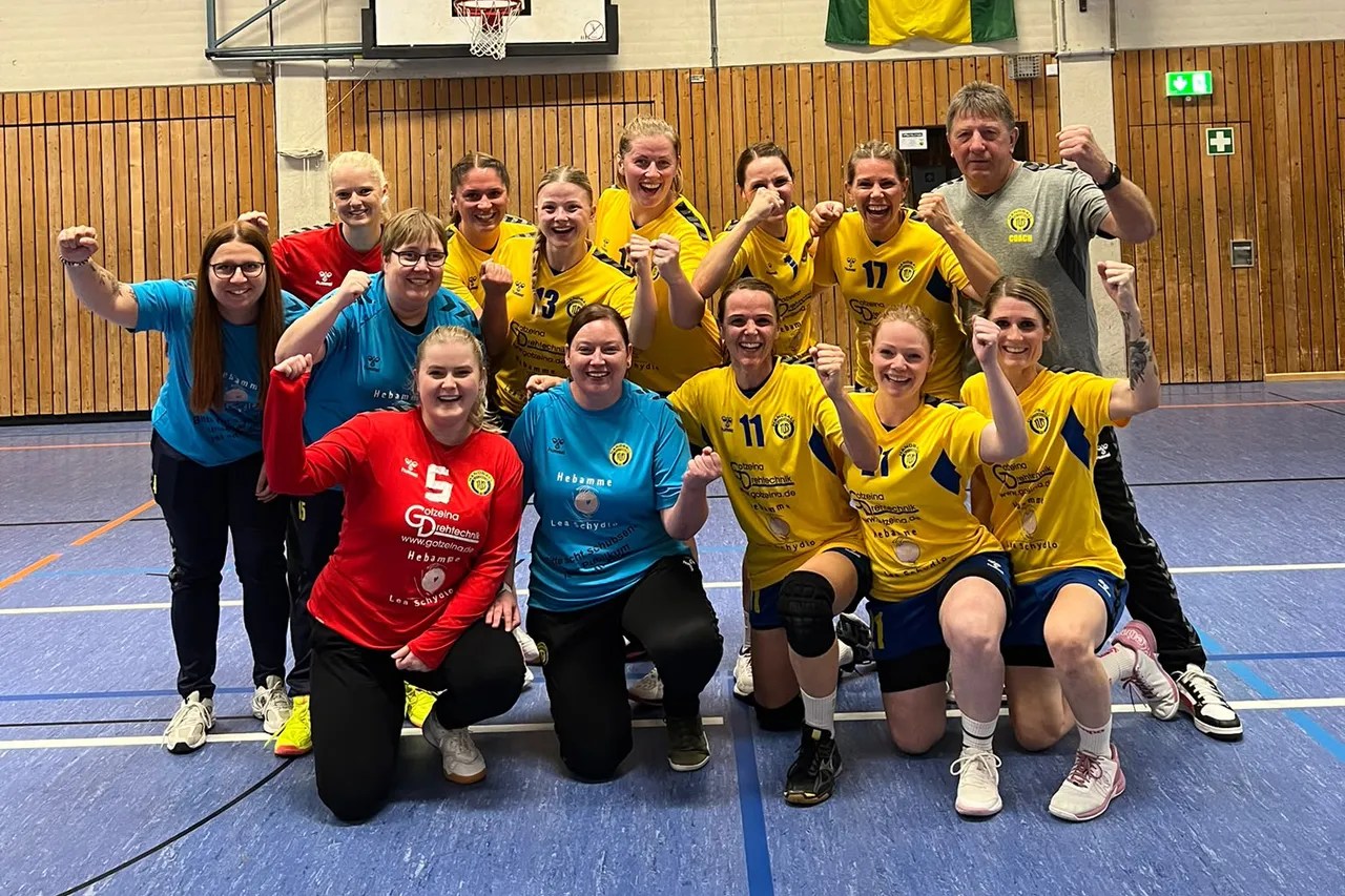 Eine Gruppe jubelnder Handballerinnen des TuS Plettenberg in gelben, blauen und roten Trikots posiert in einer Sporthalle.