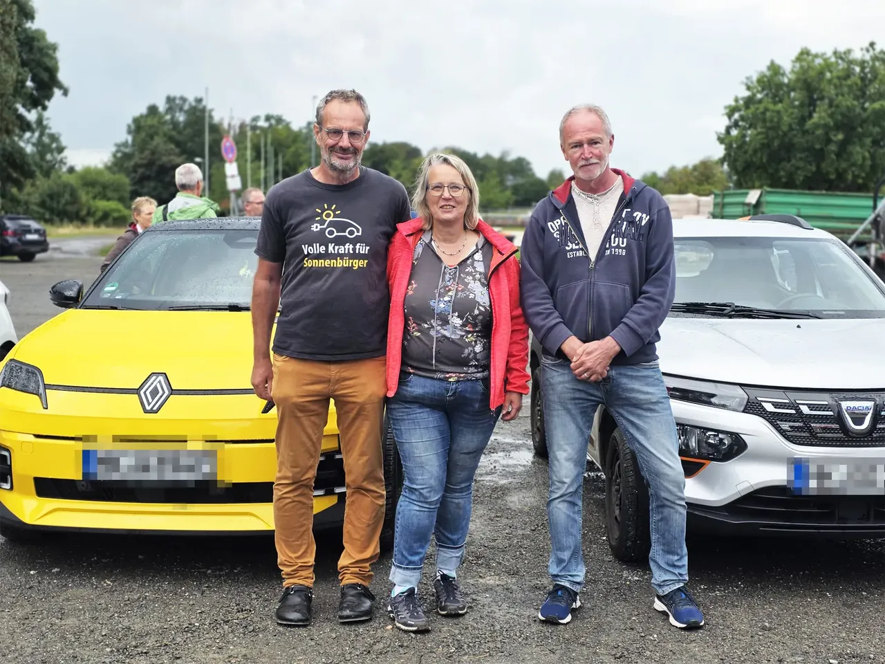 Stefan Heinrich, Carola Holz und Gerd Clever stehen vor einem gelben Renault und einem weißen Dacia.