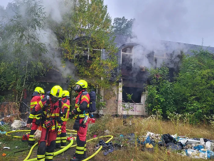 Feuerwehrleute im Einsatz vor der rauchenden Schnörrenbach-Ruine mit Feuerwehrschläuchen am Boden.