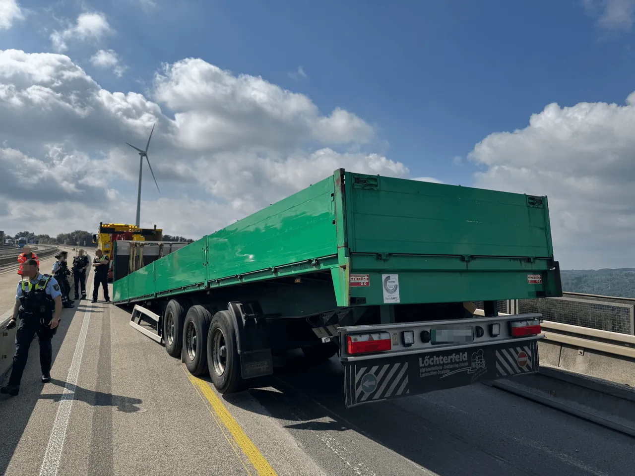 Grüner Lkw-Anhänger blockiert Fahrbahn auf der A45, während Polizisten die Situation absichern.