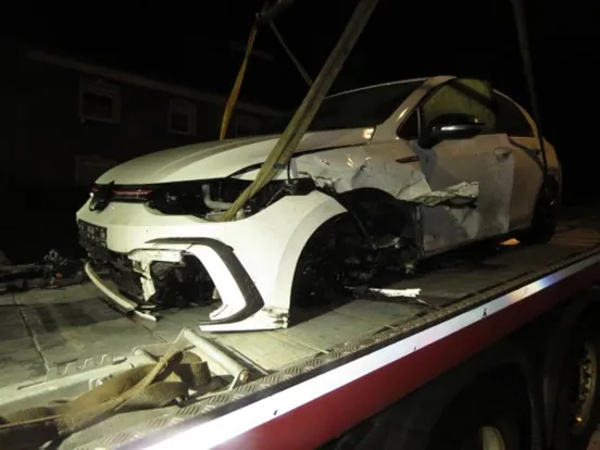 Ein weißer VW Golf mit massiven Unfallschäden an der Front und der Fahrerseite auf einem Abschleppwagen bei Nacht.