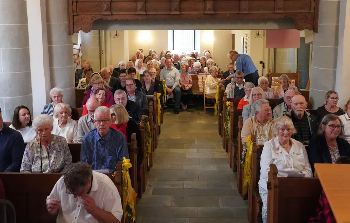 Die Gemeinde sitzt in Holzbänken in der evangelischen Kirche Ohle während der feierlichen Verabschiedung von Pfarrerin Anju Laddach.