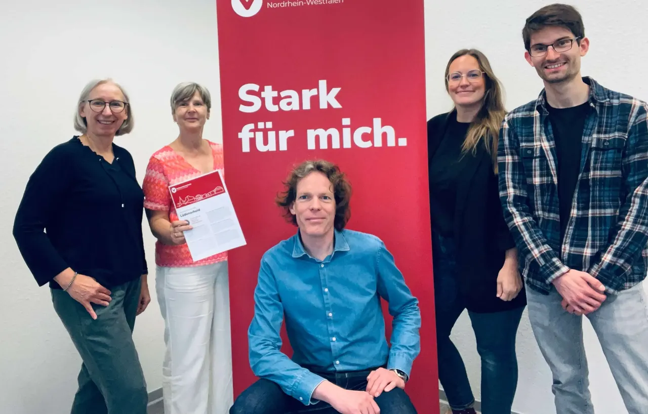 Fünf Mitarbeitende der Verbraucherzentrale Lüdenscheid stehen vor einem Banner mit dem Slogan „Stark für mich.“ und dem Logo der Verbraucherzentrale Nordrhein-Westfalen.
