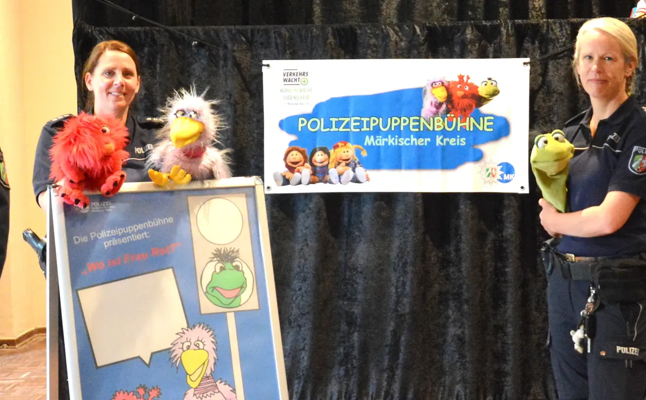 Zwei Polizistinnen präsentieren ein Puppenspiel mit bunten Tiermotiven, darunter ein roter Vogel, ein gelber Löwe und ein grünes Monster. Im Hintergrund ein Banner mit der Aufschrift