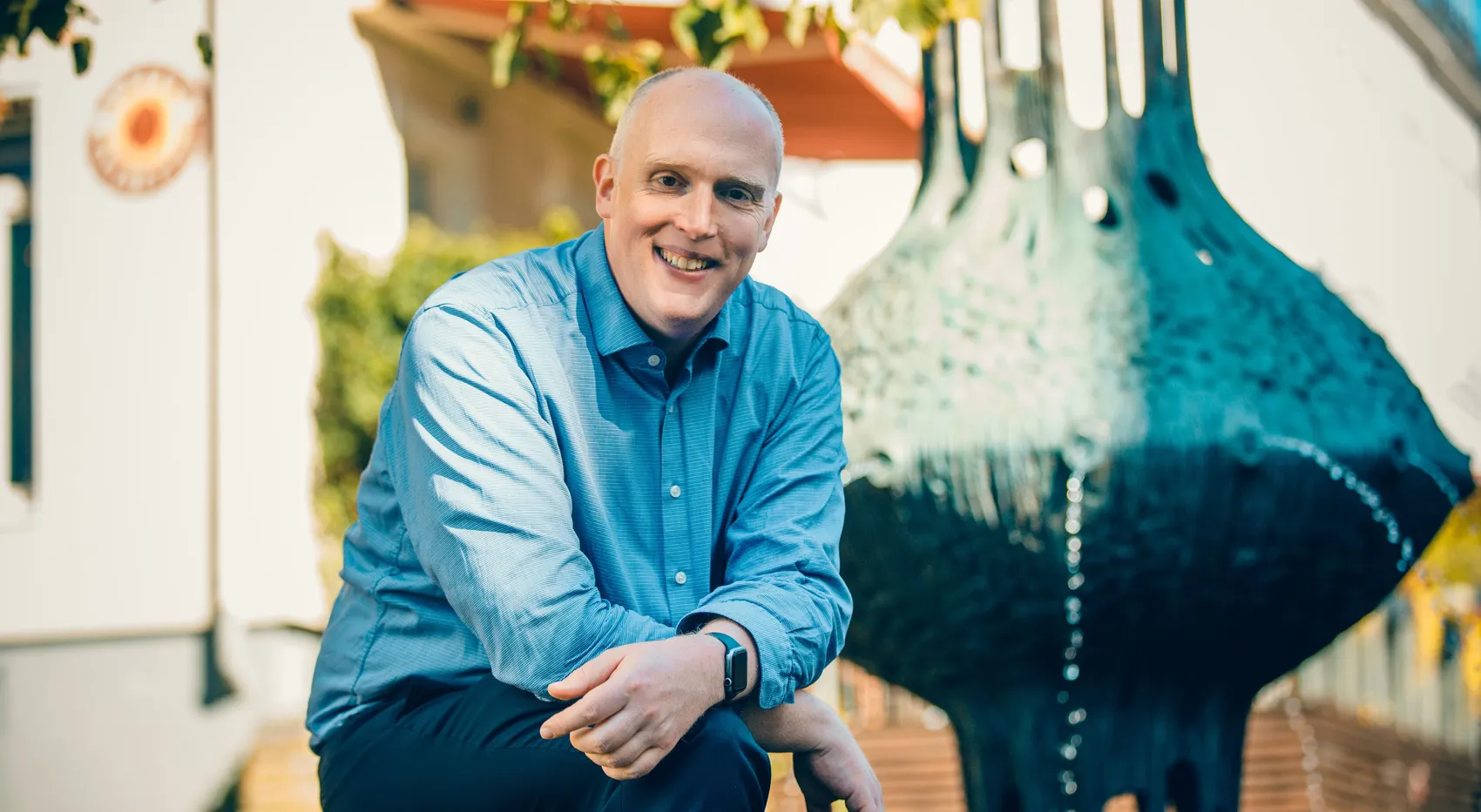 Christoph Weiland, CDU-Vorsitzender, lächelt in die Kamera, neben einer modernen Skulptur mit Wasserfall.