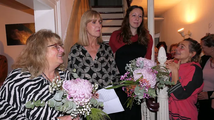 Frauen halten bei der Vernissage der Ausstellung „Zeitmangelwesen“ in der Werkstatt Plettenberg Blumensträuße.