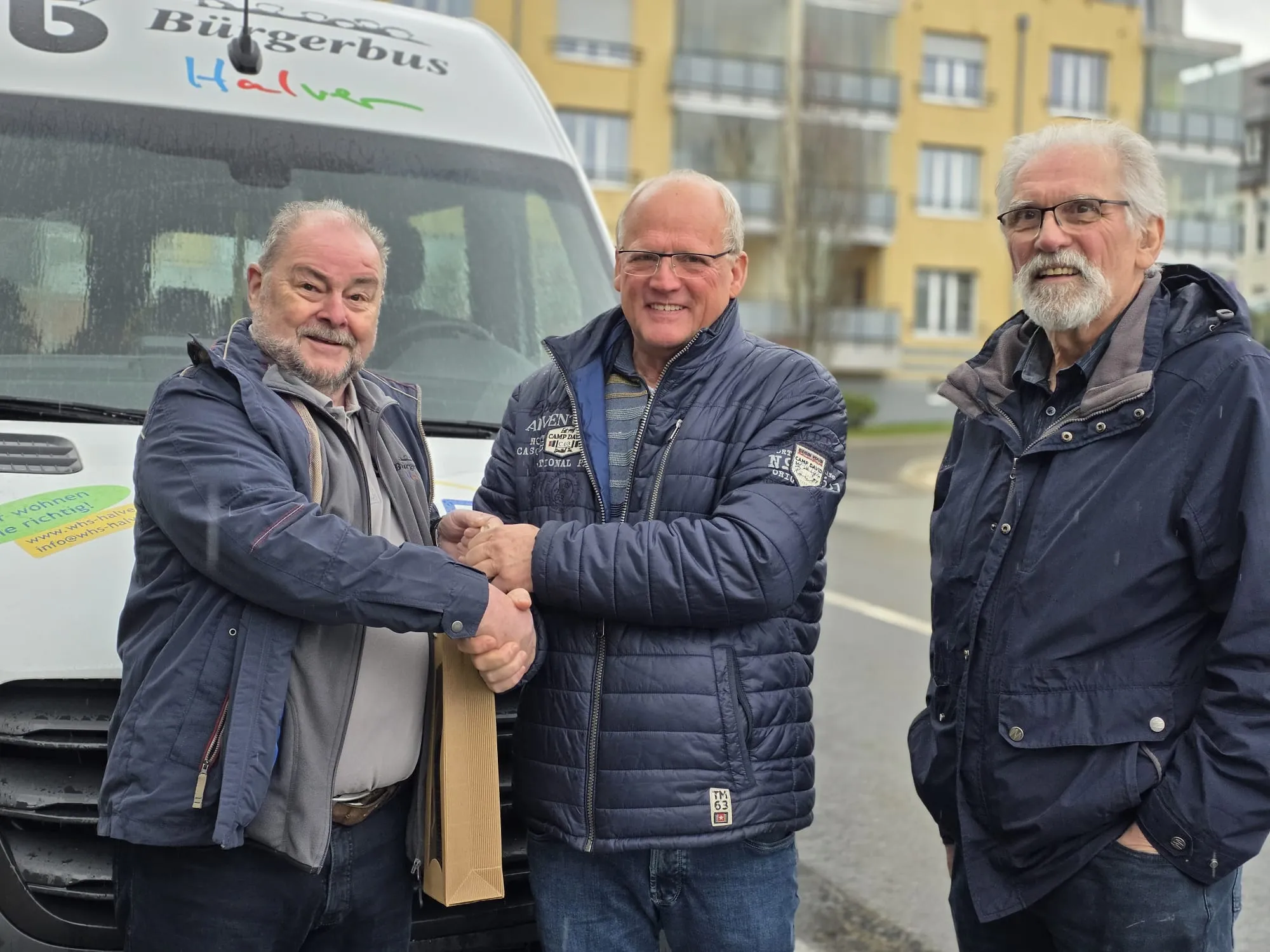 Drei Männer vor einem gelben Kleinbus mit der Aufschrift „Bürgerbus Halver“ geben sich die Hände. Links Klaus-Peter Viebahn, in der Mitte der neue Fahrer Jürgen Gottemeier und rechts Richard Raatz.