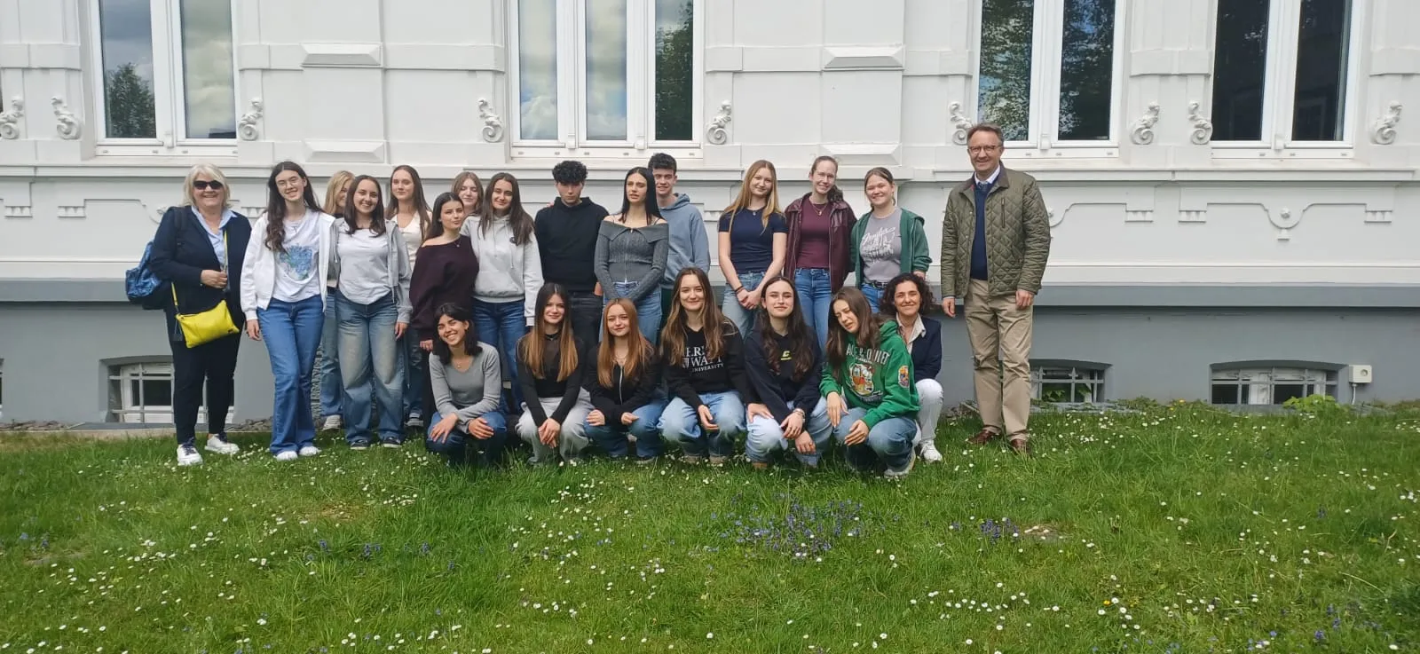 Gruppe von Schülerinnen und Schülern sowie zwei Lehrkräften vor einem hellen Gebäude auf einer grünen Wiese. Der Austausch findet zwischen dem AFG und dem Instituto Soleri Bertoni aus Italien statt.