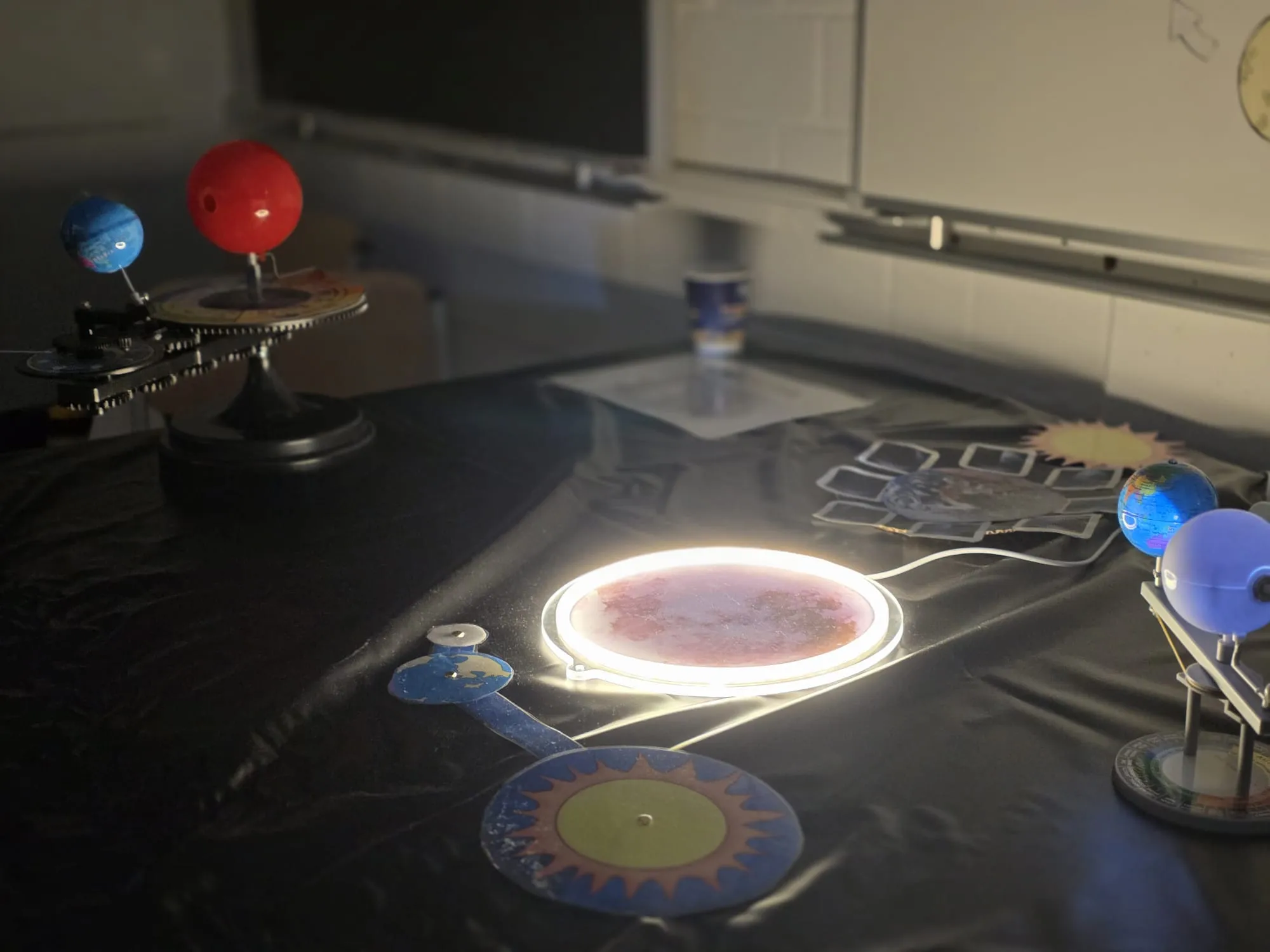 Modell des Sonnensystems mit leuchtendem Mars im Zentrum steht auf einem Tisch, umgeben von Pappsonnen und Planetenmodellen.