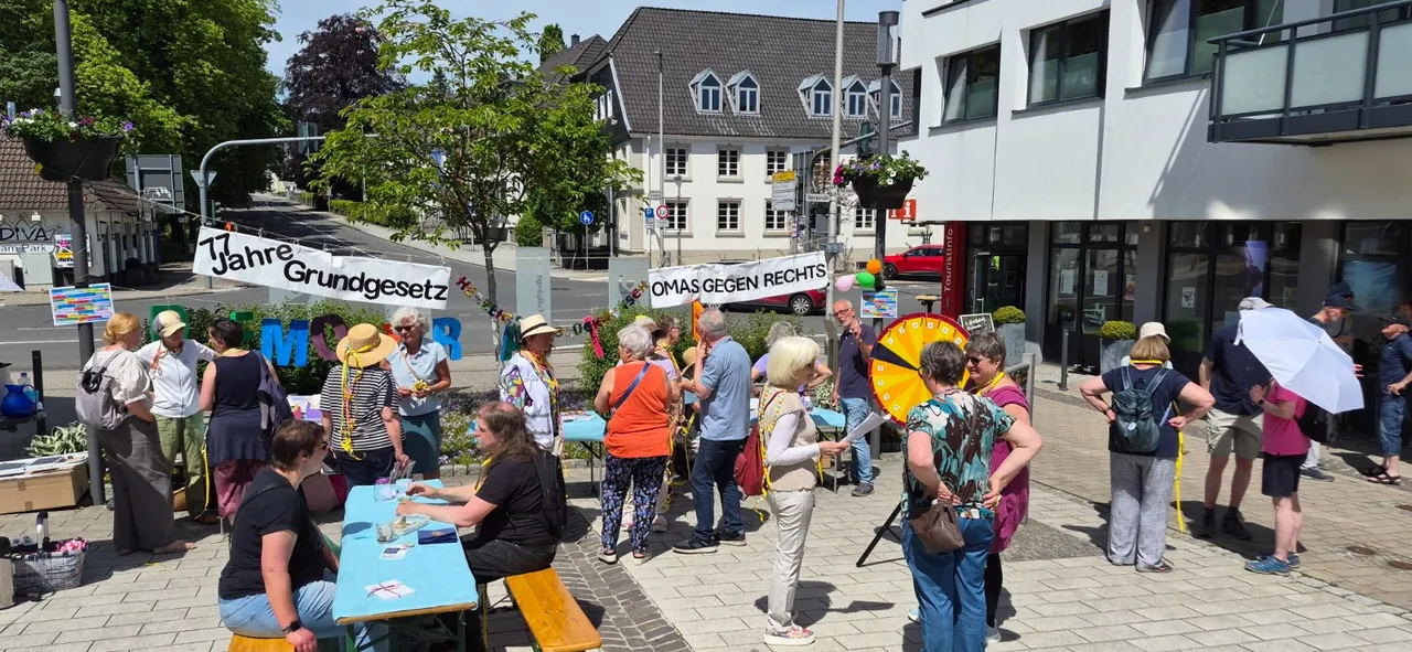 Demonstranten halten Schilder mit Aufschriften wie „77 Jahre Grundgesetz“ und „Omas gegen Rechts“ in einer Fußgängerzone.