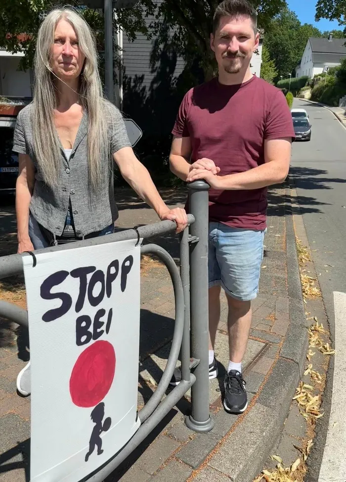 Petra Günther und Steffen Wieland stehen an einem Geländer mit einem Banner, auf dem „STOPP BEI“ und ein roter Kreis mit einer Silhouette zu sehen sind.