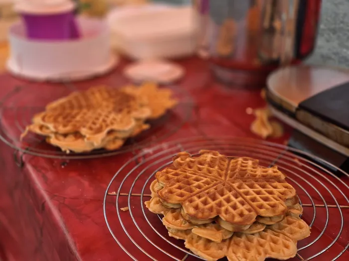 Blumenförmige Waffeln auf Drahtgittern auf einem roten Tisch.