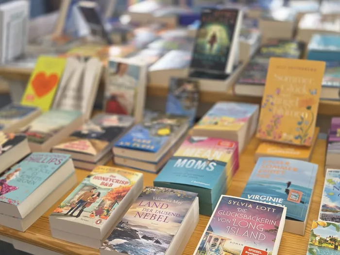 Verschiedene Bücher liegen aufgereiht und teilweise gestapelt auf einer Holzoberfläche.