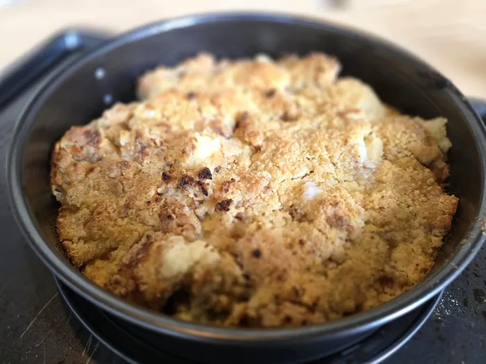 Goldbraun gebackener Apfel-Crumble in einer schwarzen Backform.