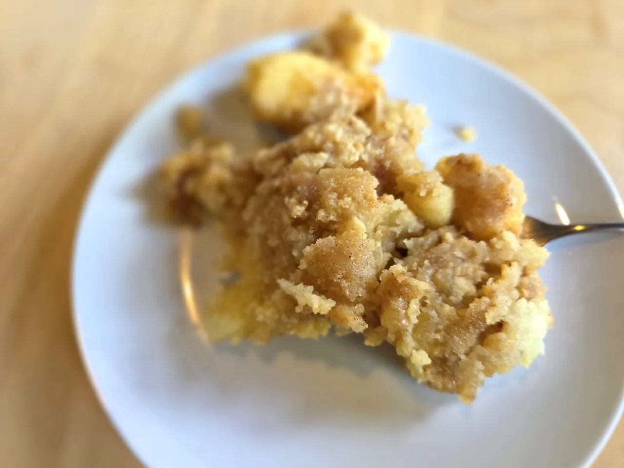 Ein Stück Apfel-Crumble mit Apfelstücken auf einem weißen Teller.