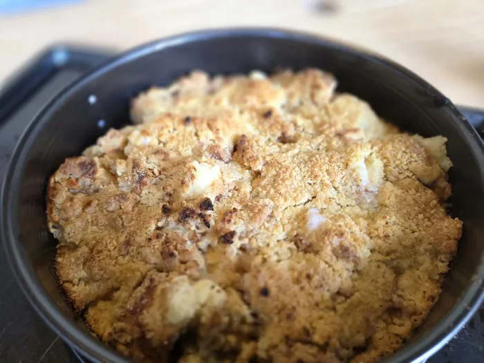Goldbrauner Apfel-Crumble mit knuspriger Streuselkruste in einer schwarzen Backform.