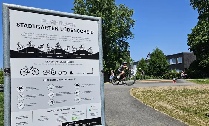 Pumptrack in Lüdenscheid mit Hinweisschildern zu Nutzung und Sicherheit, daneben Kinder beim Tanzen und Bewegen.