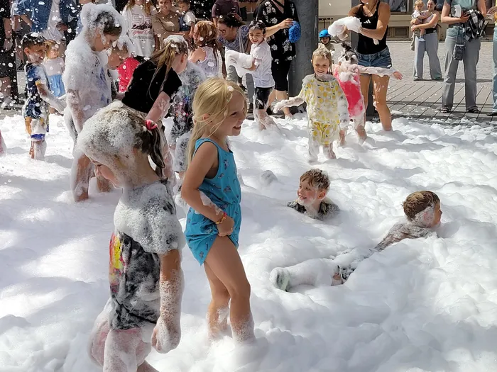 Kinder spielen in einer großen Menge weißem Schaum bei einer Schaumparty auf dem Alten Markt.