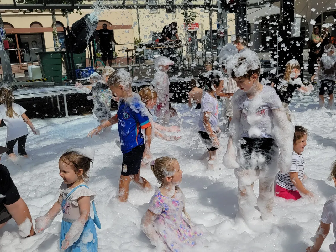 Kinder spielen in einer dichten Schicht aus weißem Schaum bei einer Schaumparty auf dem Alten Markt.