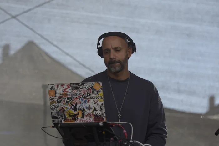 Shorty mit Kopfhörern blickt auf einen mit vielen bunten Stickern beklebten Laptop.
