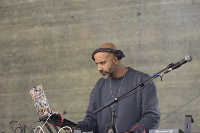 Shorty mit Kopfhörern blickt auf einen mit Aufklebern bedeckten Laptop.