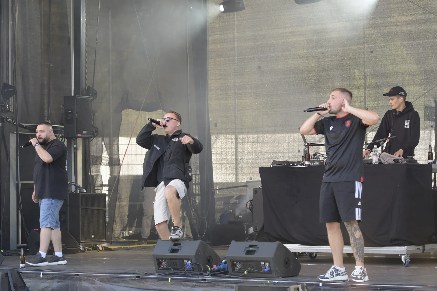 Drei Mitglieder der Allwettercrew performen auf der Collabo Stage beim Bautz 2026, während ein DJ im Hintergrund am Mischpult steht.