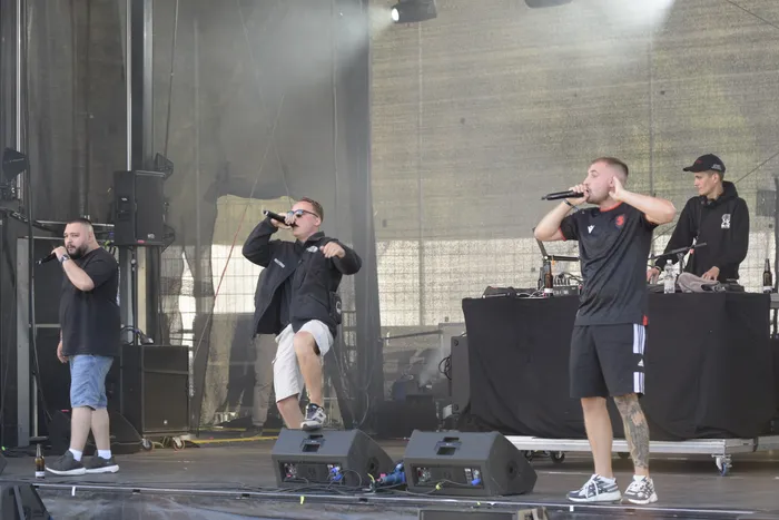 Drei Mitglieder der Allwettercrew performen auf der Collabo Stage beim Bautz 2026, während ein DJ im Hintergrund am Mischpult steht.
