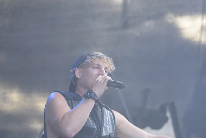 Ein Mann mit blonden Locken und einer dunklen Kappe singt in ein Mikrofon auf der Junior Carl Collabo Stage.