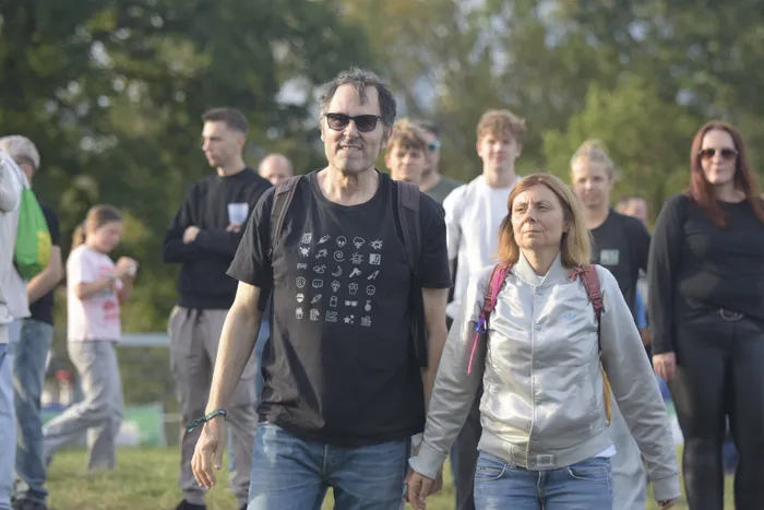 Ein Mann in einem schwarzen T-Shirt mit weißen Symbolen und eine Frau in einer silbernen Jacke gehen durch eine Menschenmenge bei der Bautz 2026.