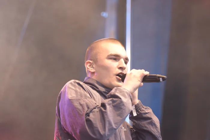 Der Künstler Hexer singt in ein Mikrofon während eines Auftritts auf der Collabo Stage.