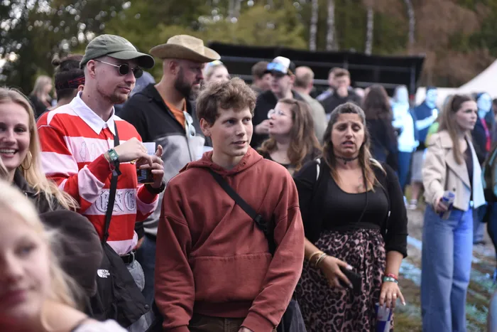 Eine Gruppe junger Menschen steht in einer Menschenmenge bei einem Open-Air-Event.