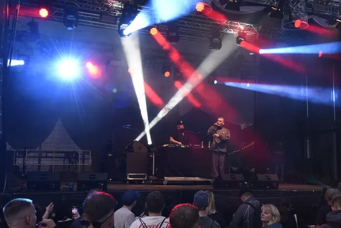 Hexer performt auf der Collabo Stage unter intensiver roter, blauer und weißer Bühnenbeleuchtung.