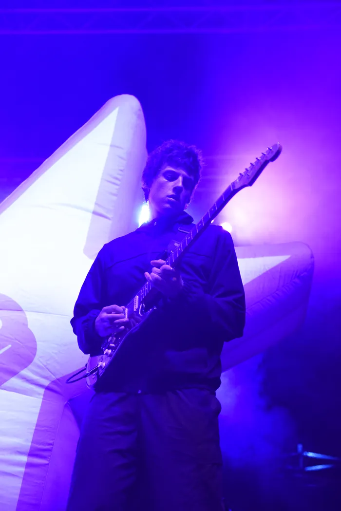 Sampagne spielt E-Gitarre vor einem großen weißen aufblasbaren Stern unter blauem und violettem Bühnenlicht.