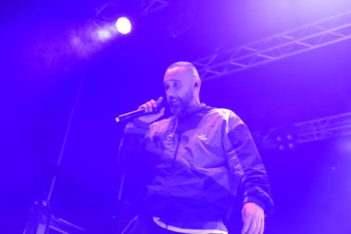 Azad singt unter violettem Bühnenlicht in ein Mikrofon.
