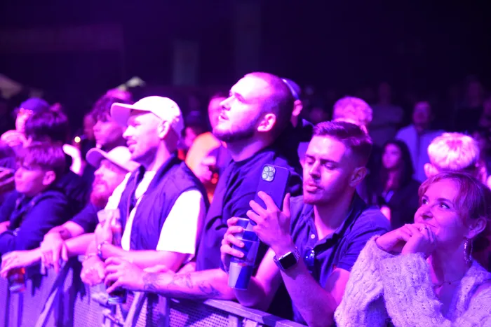 Zuschauer bei einem Konzert unter violettem Licht blicken in Richtung der Bühne.