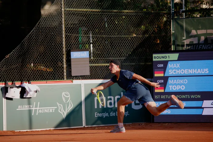 Max Schönhaus in einer dynamischen Bewegung mit dem Tennisschläger auf einem Sandplatz während eines Matches.