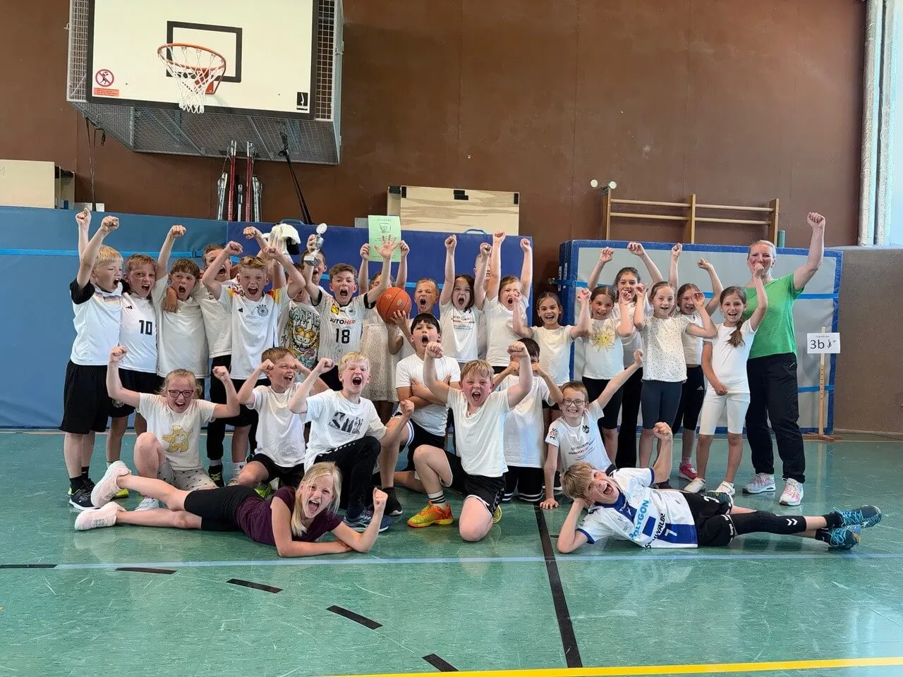 Jubelnde Kinder der Klasse 3b mit Basketball und Trainerin nach dem Gewinn des Basketballturniers der Bismarckschule Kierspe.