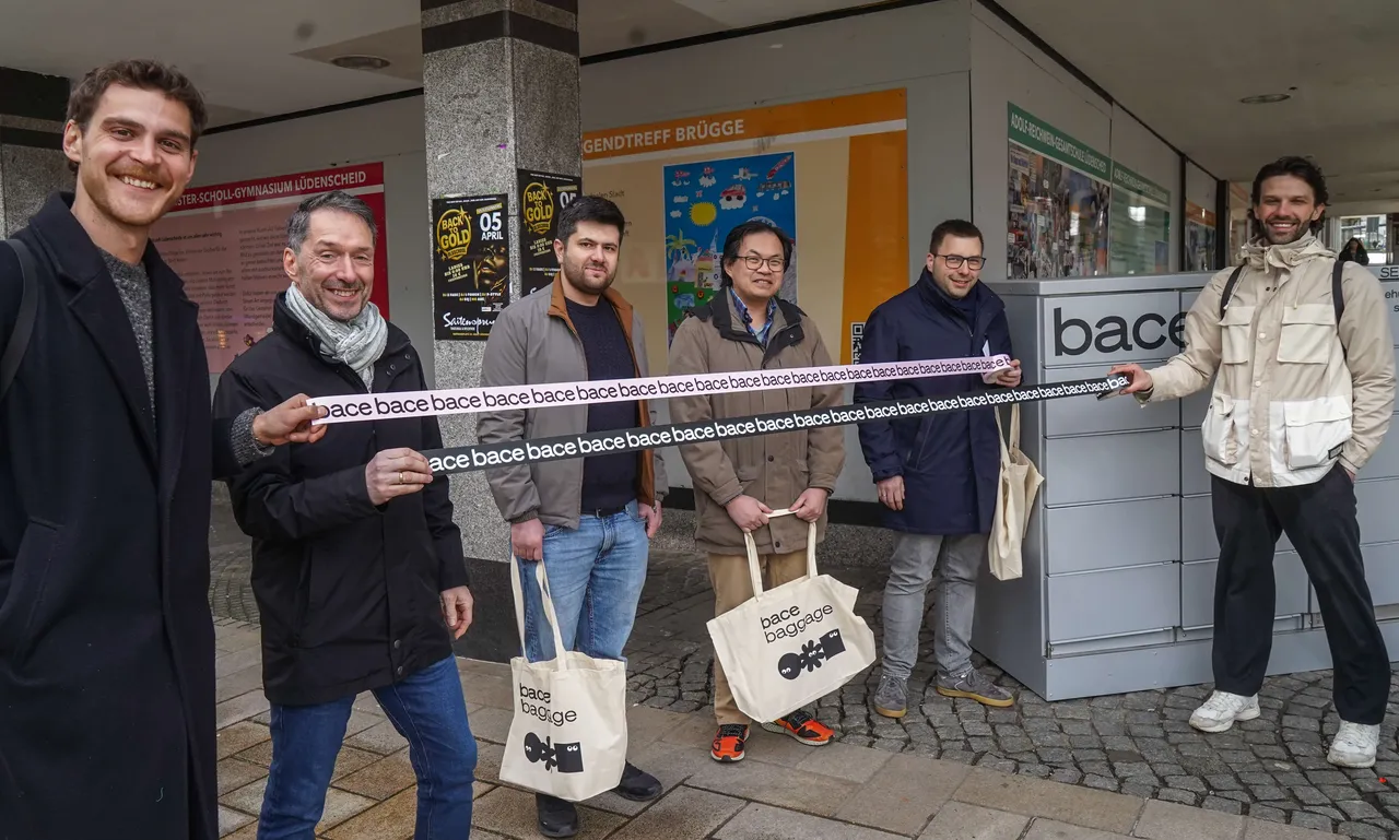 Sechs Männer stehen vor einem grauen Kasten mit der Aufschrift „bace“ und halten Einkaufstaschen mit dem gleichen Schriftzug. Sie repräsentieren die Unternehmen bace, Hirschapotheke, Engelapotheke und Optik Lüttringhaus.