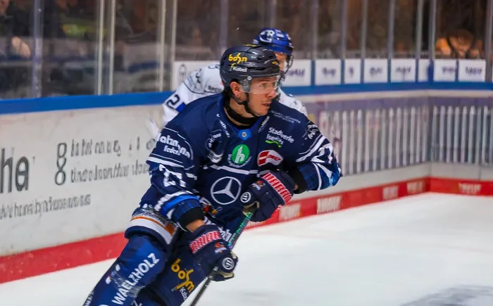 Christian Thomas in blauem Eishockey-Trikot mit Helm und Schläger auf dem Eis.