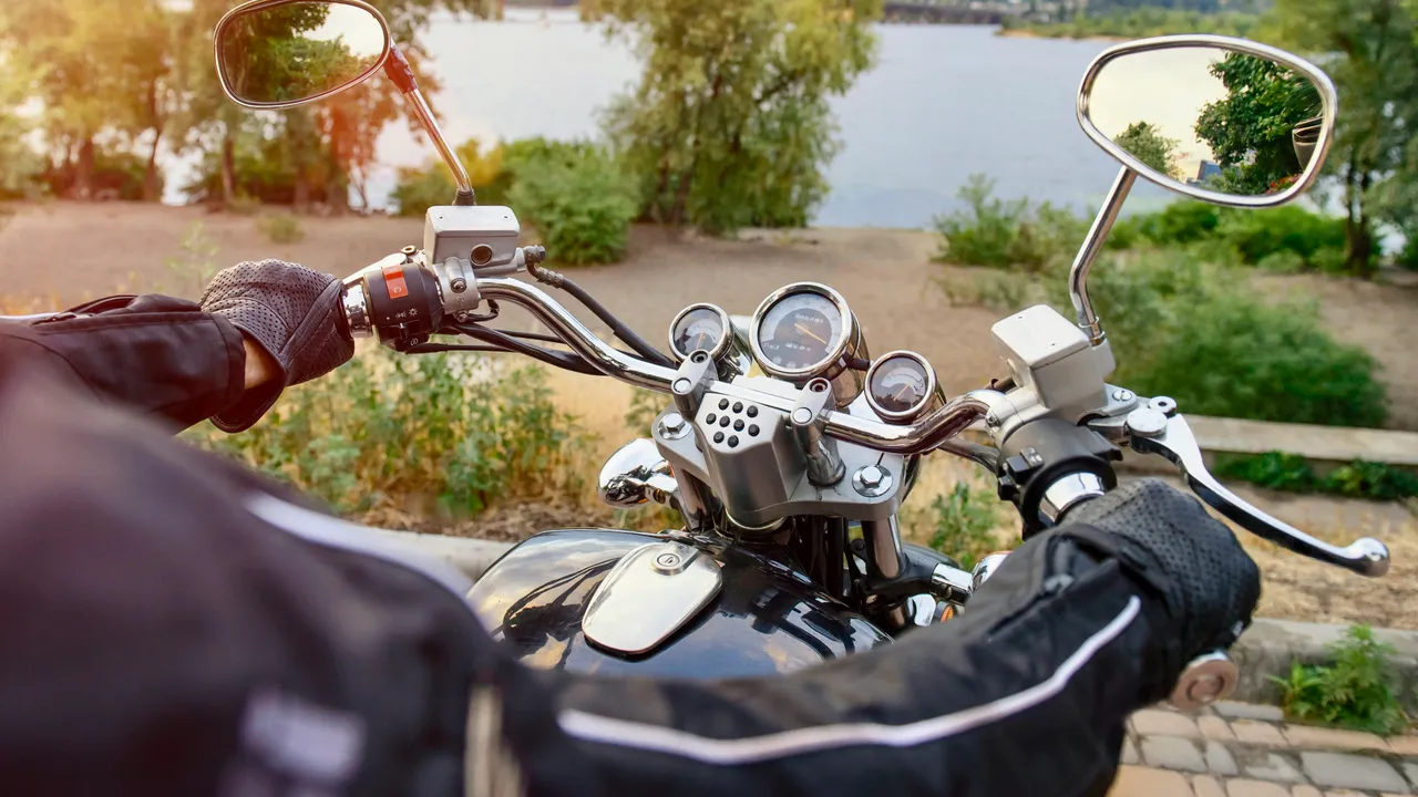 Motorradlenker mit Chromdetails und Blick auf einen See im Hintergrund.