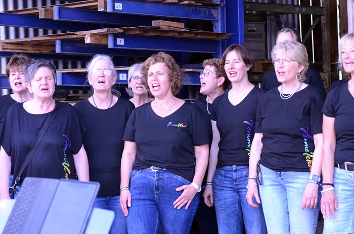 Chor „Femmevokal“ singt auf der Bühne des Immecke Rock Festivals in Plettenberg. Die Sängerinnen tragen schwarze T-Shirts und zeigen beim Singen offene Münder.