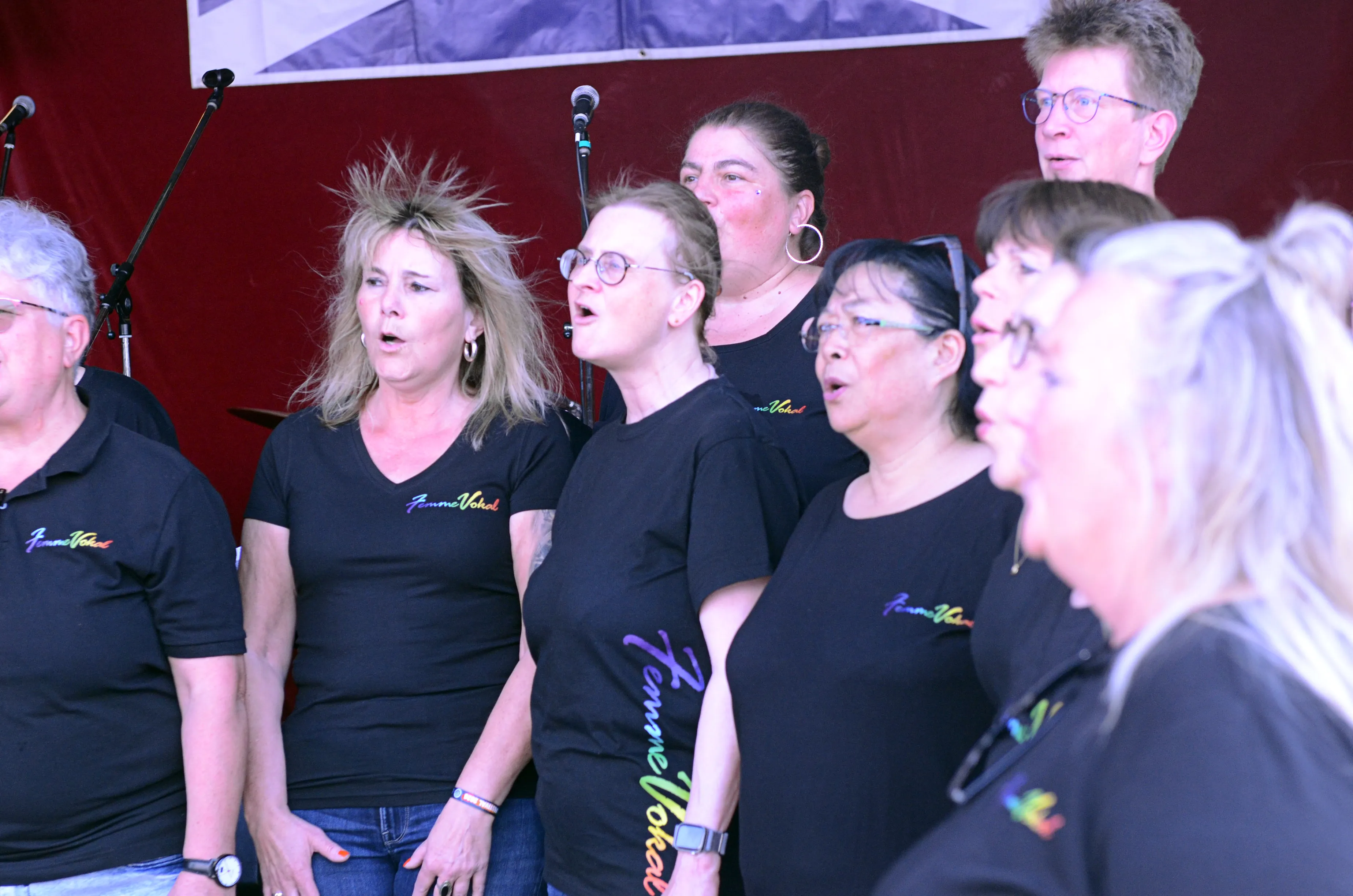 Chor „Femme Vokal“ singt auf der Bühne des I-Rock Festivals in Plettenberg. Die Sängerinnen tragen schwarze T-Shirts mit dem Schriftzug des Chors.