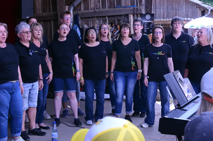 Chor „Femme Vokal“ singt auf der Bühne des I-Rock Festivals in Plettenberg. Die Mitglieder tragen schwarze T-Shirts mit dem Schriftzug des Chors.