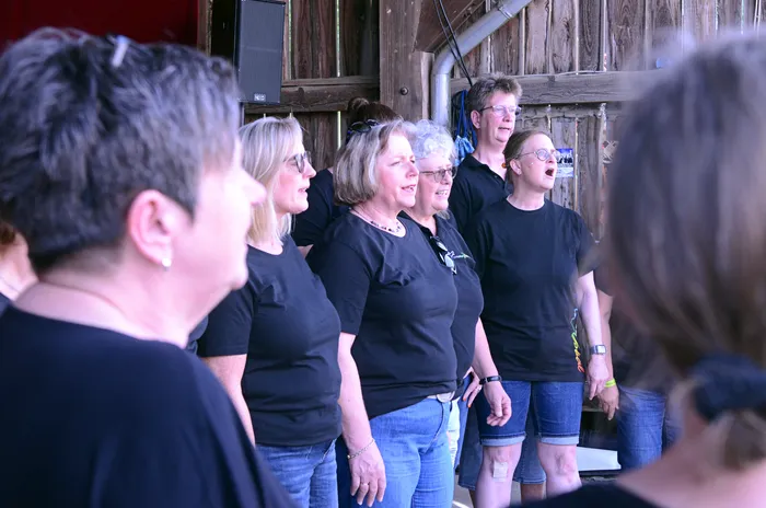 Frauenchor singt auf der Bühne des I-Rock Festivals in Plettenberg. Die Sängerinnen tragen schwarze T-Shirts und Jeans.