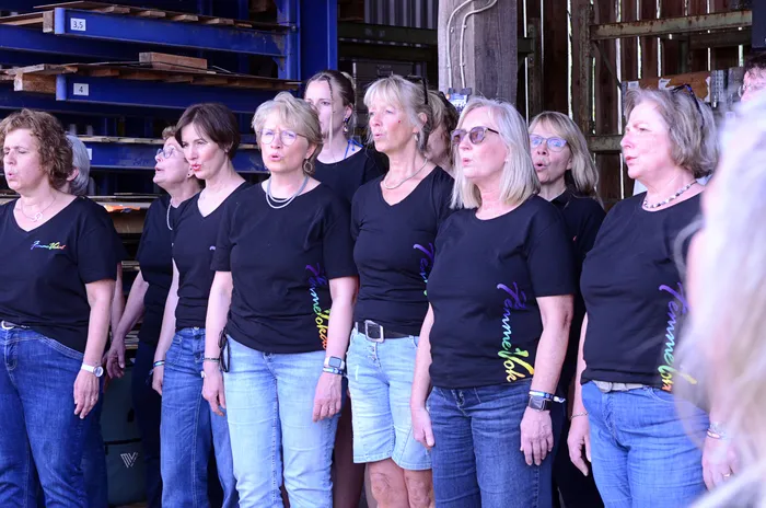 Chor „Femmevokal“ singt auf der Bühne des I-Rock Festivals in Plettenberg. Die Sängerinnen tragen schwarze T-Shirts mit violettem Aufdruck und Jeans.