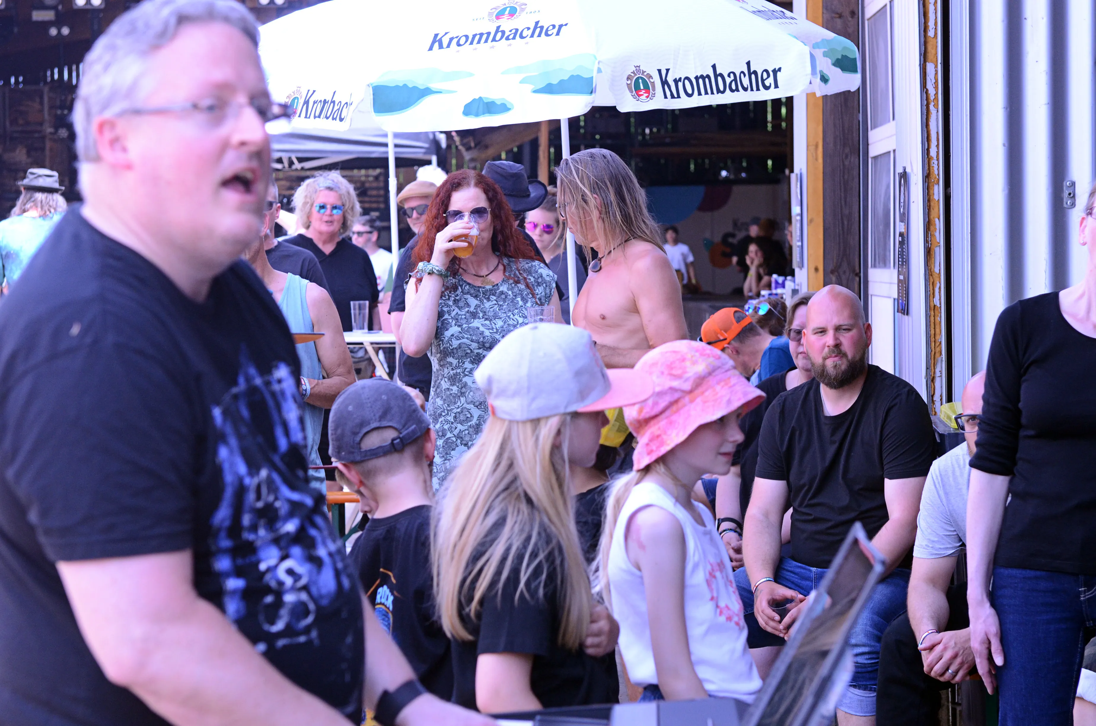 Menschenmenge vor einer Bühne mit Sonnenschirmen der Marke Krombacher auf dem Immecke Rock Festival in Plettenberg.