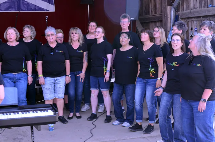 Chor „Femme Vocal“ singt auf der Bühne des I-Rock Festivals in Plettenberg. Die Gruppe besteht aus etwa 15 Frauen, die schwarze T-Shirts und Jeans tragen.