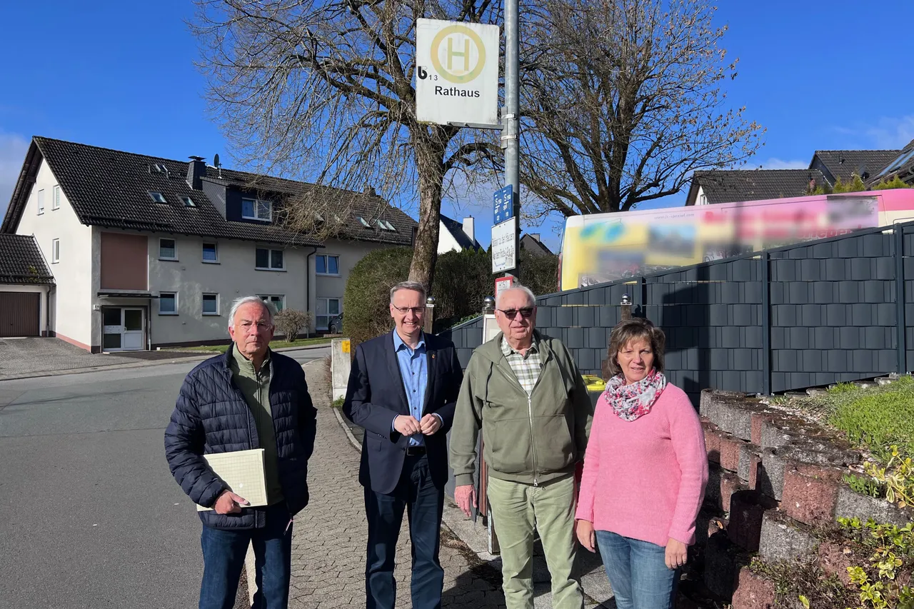 Vier Personen stehen vor dem Rathaus Herscheid und halten Werbematerial für den Bürgerbus. Im Hintergrund ist ein Straßenschild mit der Aufschrift „Rathaus“ zu sehen.